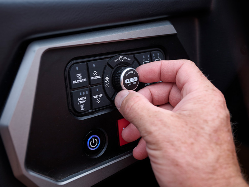 A hand turns the cruise-control dial on an Axis dash panel, surrounded by tactile buttons for the Wedge, blower, and anchor/navigation lights.