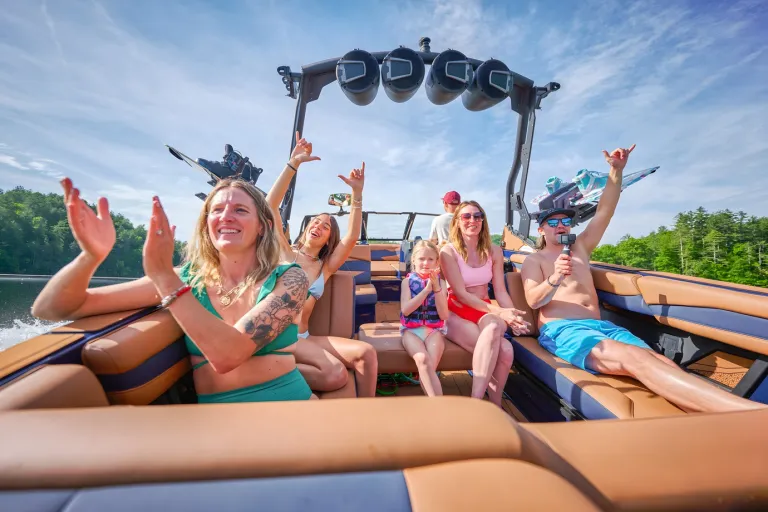A cheering family fills the tan cockpit of an Axis A245, a small child among them, riding across a forested lake.